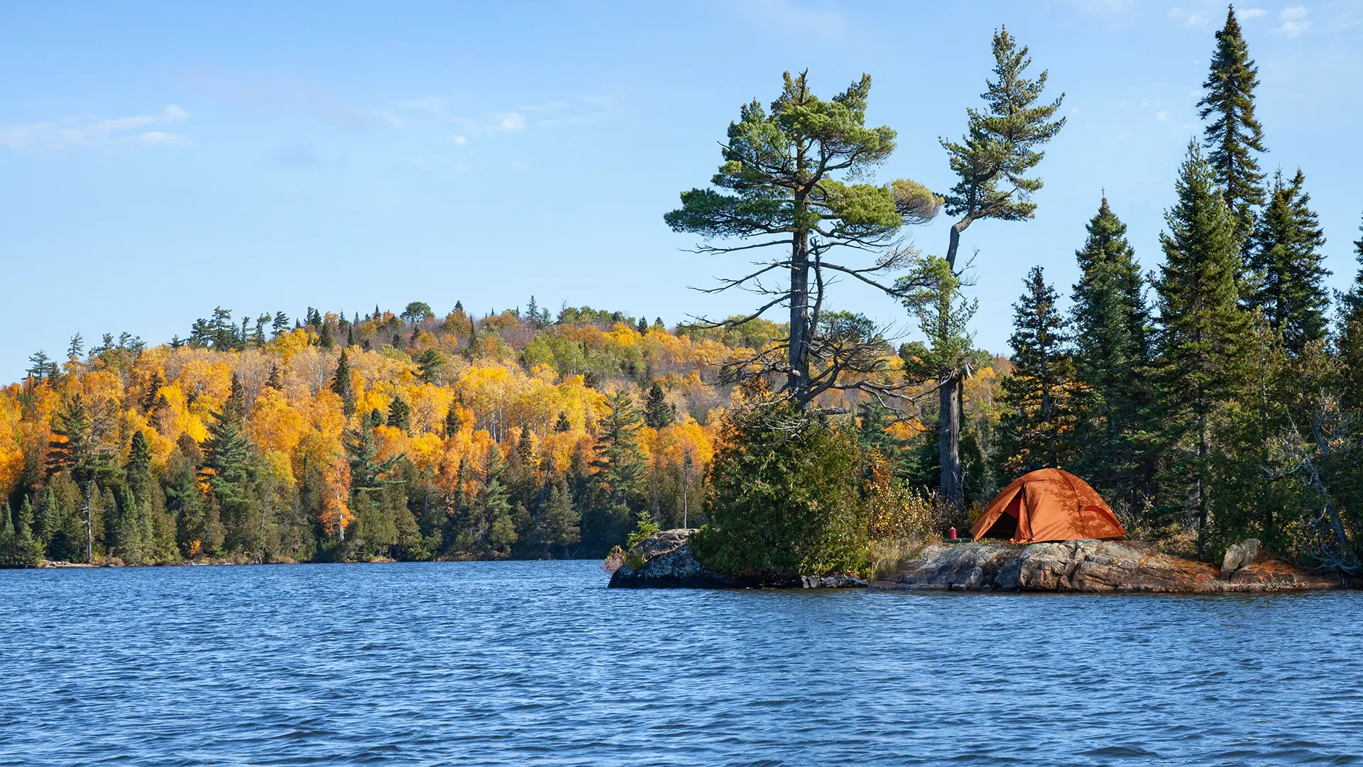Orange tent on the rocky shore