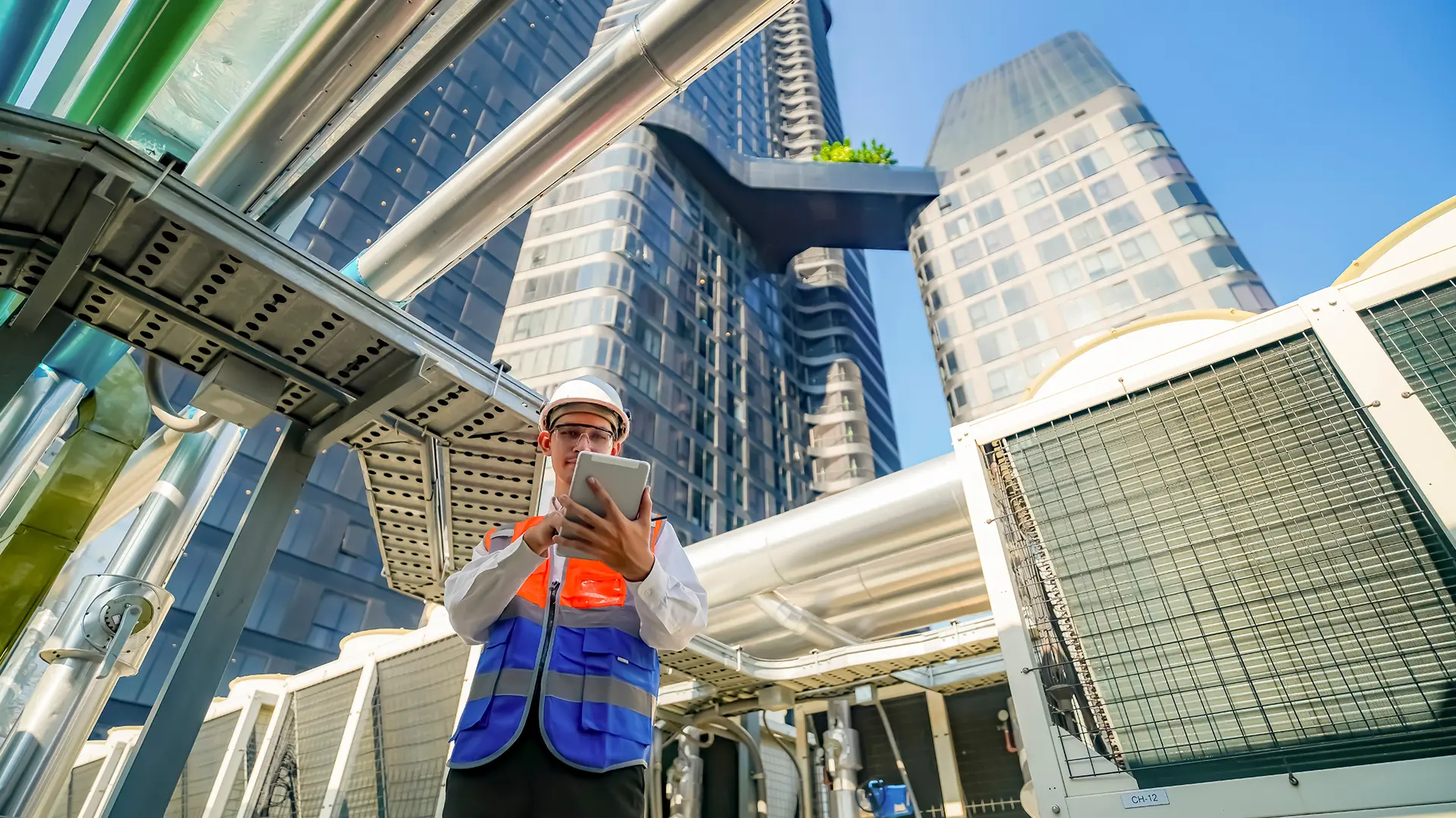 A worker assesses HVAC equipment on a rooftop