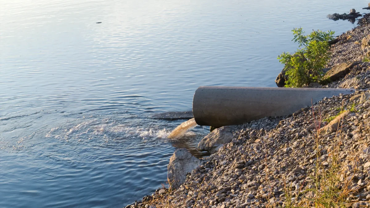 The sewage flows from the pipe into the river